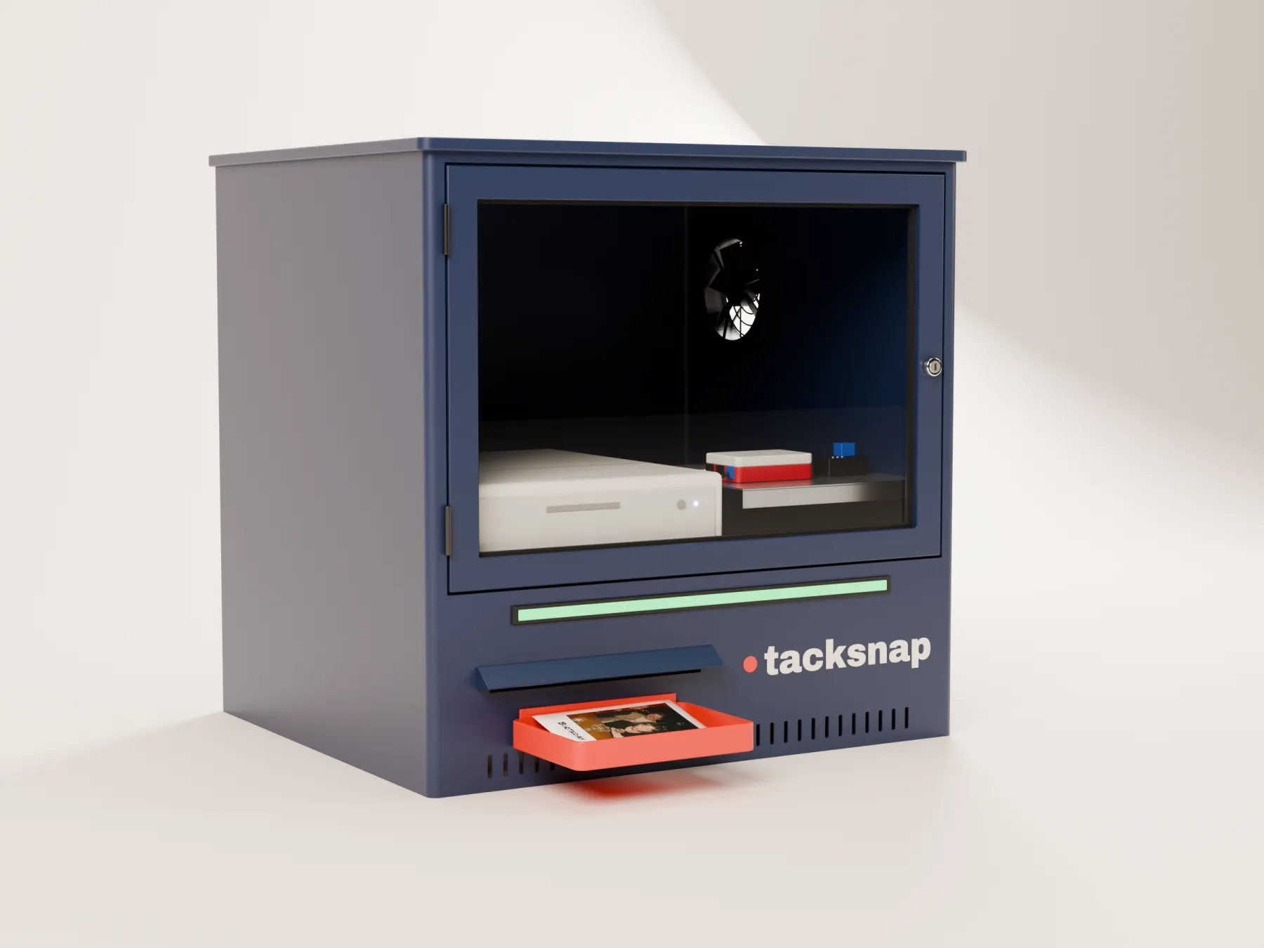 The Tacksnap Box: a navy steel cabinet with a glass door showing the printer inside, a green status light and a red print tray